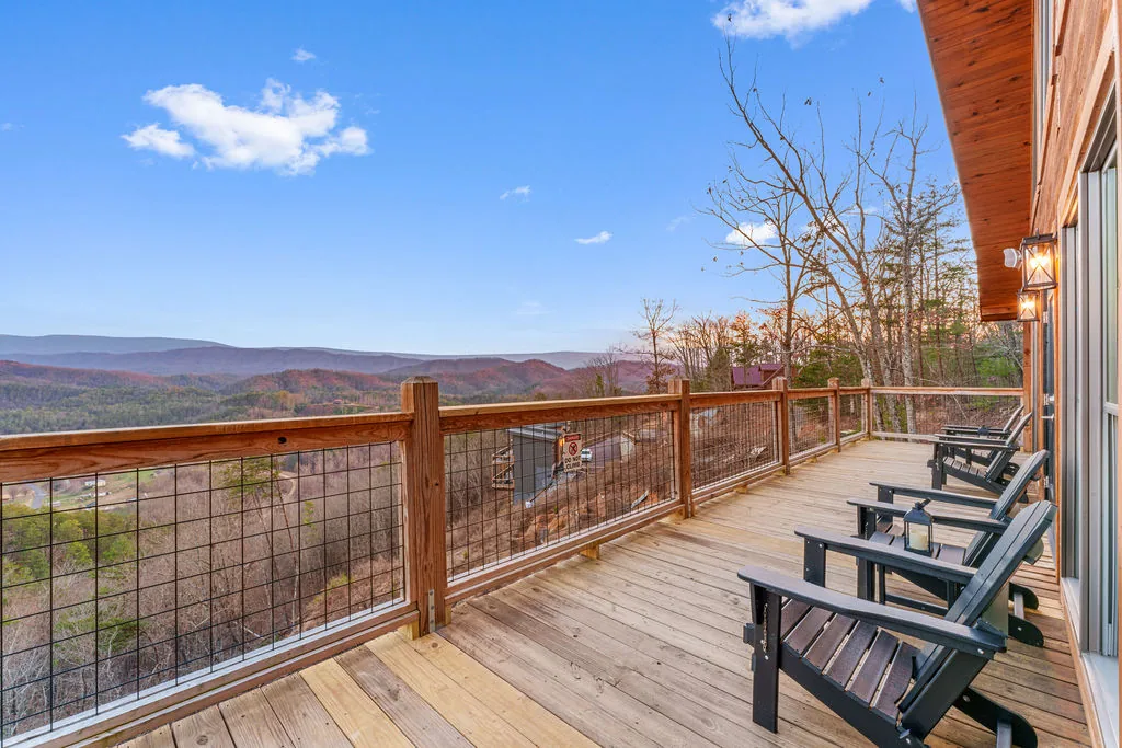 Wraparound deck with Adirondack chairs and an uninterrupted view over the valley