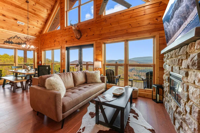 The main-level living room at Rylan's Mountain Retreat with a stone fireplace and windows facing the mountains